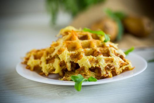 fried potato waffles with cheese in a plate on a light wooden table.