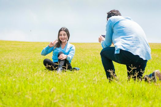 Two friends taking photos with the cell phone in the field, A guy taking a picture of a girl in the field, Boyfriend taking a picture of his girlfriend in the field