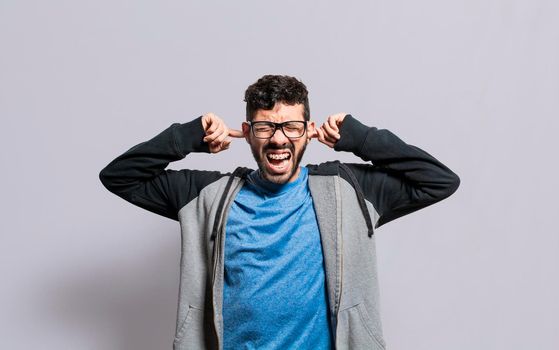 Irritated person screaming covering his ears, desperate person avoiding hearing bad news, stressed man screaming covering his ears