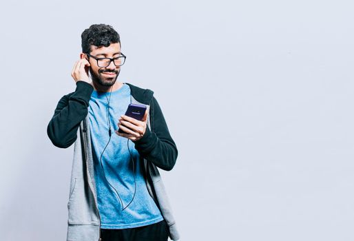 Person listening to music with his cell phone with headphones isolated, people enjoying music with headphones isolated, cheerful guy listening to music with his cell phone isolated