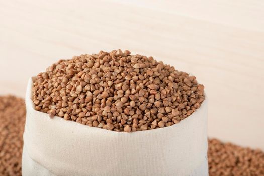 Buckwheat harvest. Poor agricultural harvests, food shortages, world hunger. A bag of buckwheat on a brown background .