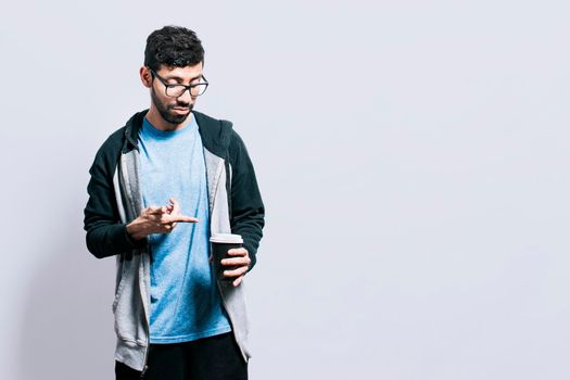 Person with coffee on isolated background, guy pointing disposable cup of coffee on isolated background, concept of a man showing looking at disposable cup of coffee