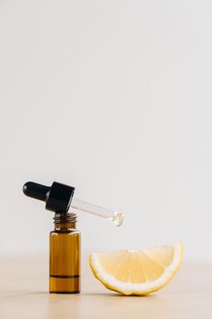 Essential oil in one bottle and lemon lying on the surface.