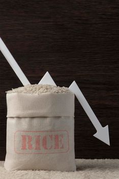 Rice harvest. Poor agricultural crops, food shortages, world hunger. A bag of rice on a brown background with a white arrow pointing down