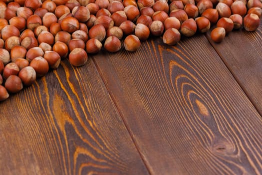hazelnuts with shells laid on brown wooden table surface with diagonal composition and copy space