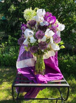 Romantic festive bouquet of irises, aliums and other spring flowers in the garden. Home decor and flowers arranging.