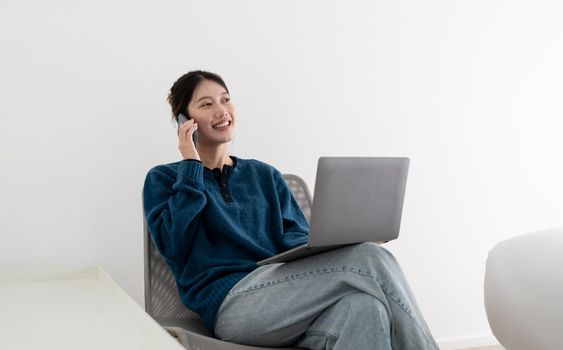 Portrait of smiling beautiful business asian woman using laptop computer and calling byh mobile phone from home concept.