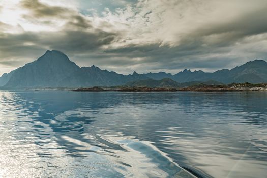 Norwegian seascape, lighthouse on the island, rocky coast with dramatic skies, the sun breaks through the clouds, sheer cliffs, small islands illuminated by the sun. High quality photo