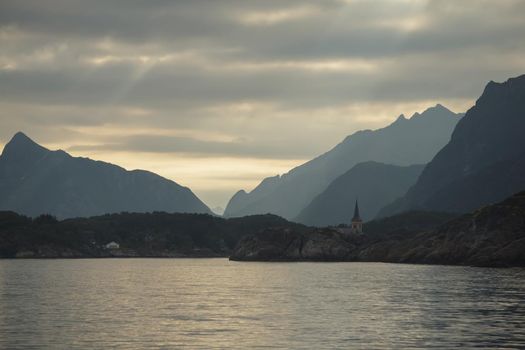 Norwegian seascape, rocky coast with dramatic skies, the sun breaks through the clouds, sheer cliffs, small islands illuminated by the sun. High quality photo