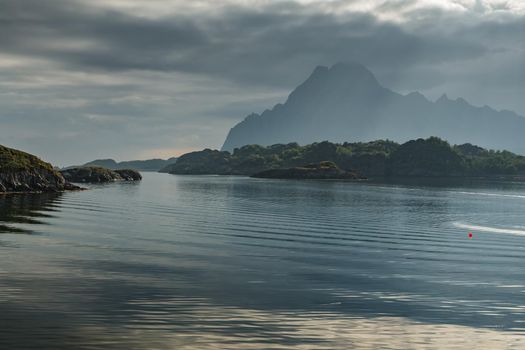 Norwegian seascape, rocky coast with dramatic skies, the sun breaks through the clouds, sheer cliffs, small islands illuminated by the sun. High quality photo