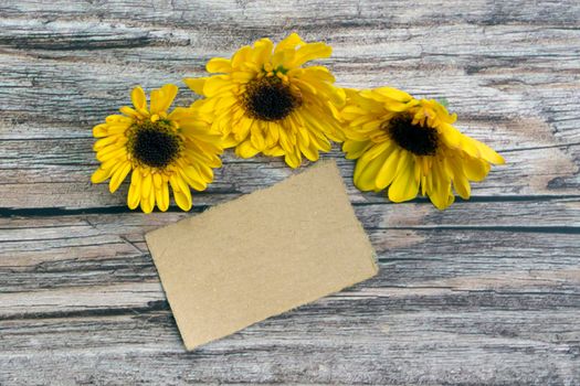Torn brown paper on wooden surface and sunflower flat lay with copy space. Directly above.