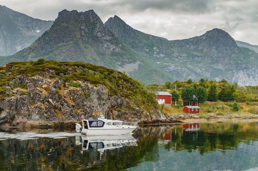 a small white fishing boat floats through the water along the rocks, norwegian seascape, rocky coast with dramatic skies, the sun breaks through the clouds, sheer cliffs. High quality photo