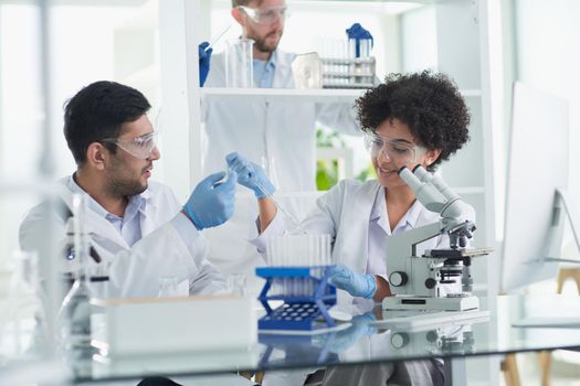 Team of Scientists Working Using Microscope, Analysing Microbiology Samples