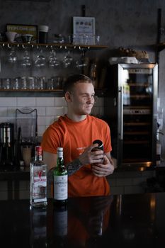Barman is making cocktail at night club. stylish young man mixing a cocktail in a dark loft cafe. alcohol drink in modern bar. male bartender.