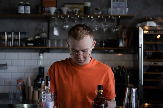 Barman is making cocktail at night club. stylish young man mixing a cocktail in a dark loft cafe. alcohol drink in modern bar. male bartender.