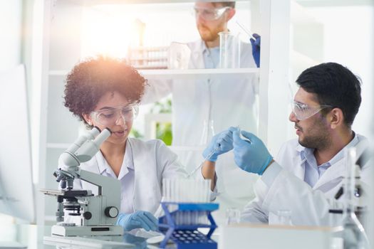 Team of Scientists Working Using Microscope, Analysing Microbiology Samples