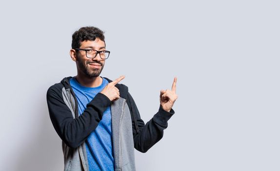 Smiling person pointing fingers to the side, smiling man recommending something with fingers on isolated background, isolated people pointing fingers at something