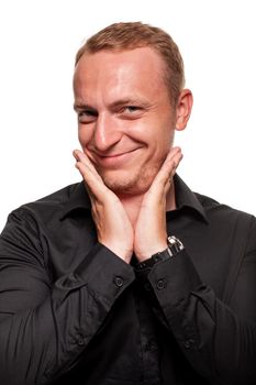 Handsome young blond man in a black shirt is making faces, smiling and touching his face, isolated on a white background