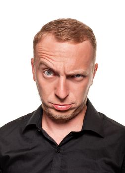 Handsome young blond man in a black shirt is making faces and grining at the csamera, isolated on a white background