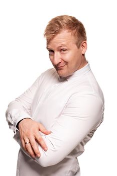 Imposing, young, blond man in a white shirt, with crossed hands is smiling, while standing sideways isolated on a white background