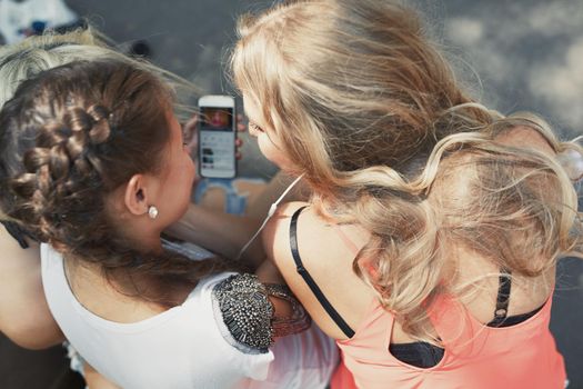 Girlfriends with smartphone having fun in social media on the city street