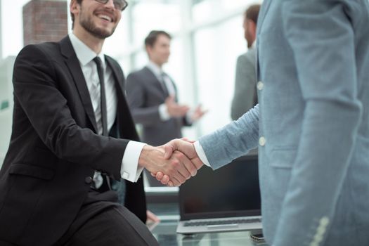 close up. happy young businessman shaking hands with his business partner. concept of cooperation