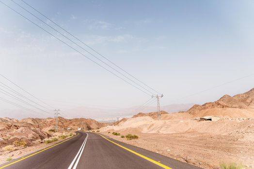 A road next to a mountainous desert landscape. Road 12 on the way to Eilat, Israel, on the Egyptian border. Mountains in different and varied sand colors. High quality photo