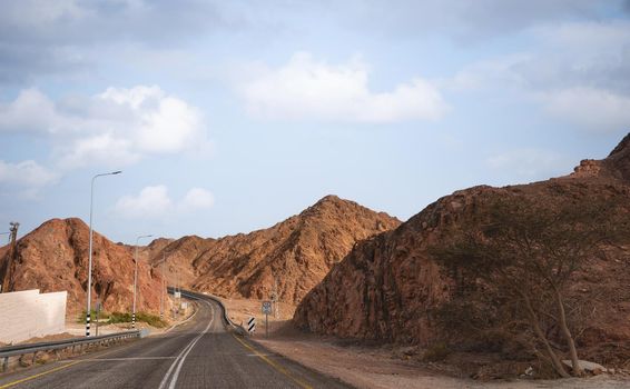 A road next to a mountainous desert landscape. Road 12 on the way to Eilat, Israel, on the Egyptian border. Mountains in different and varied sand colors. High quality photo