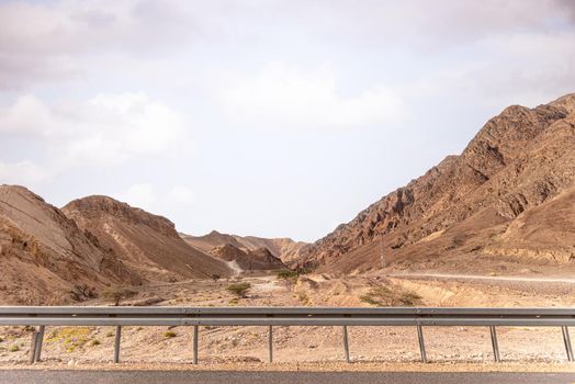 A road next to a mountainous desert landscape. Road 12 on the way to Eilat, Israel, on the Egyptian border. Mountains in different and varied sand colors. High quality photo