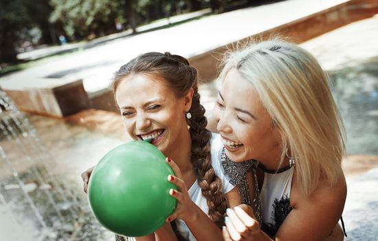 Two girlfriends having fun and blowing balloons