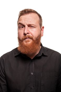 Portrait of a young, chubby, redheaded man with a beard in a black shirt, winking at the camera, isolated on a white background
