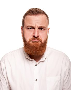 Portrait of a young redheaded man in a white shirt looking confused and making faces at the camera, isolated on a white background