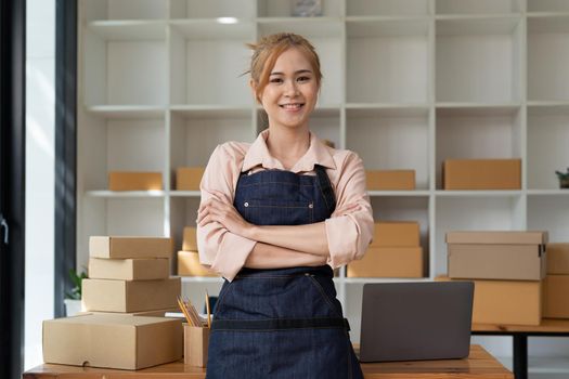 Portrait of a confidential asian woman waitress apron standing at her home with cardboard for shipping online shopping small business owner concept
