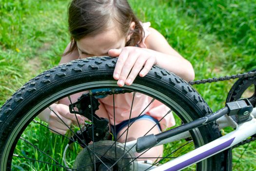 a child girl has damaged a bicycle wheel and is making repairs photo without processing. High quality photo