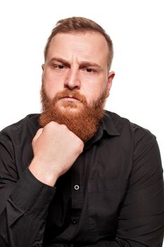 Portrait of a young, chubby, redheaded man with a beard in a black shirt, looking thoughtful and serious, isolated on a white background