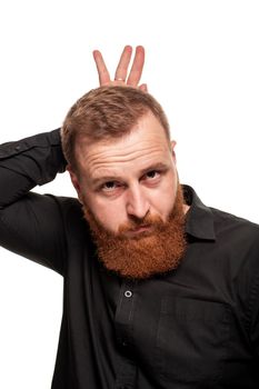 Portrait of a young, redheaded man with a beard in a black shirt, makes faces at the camera, isolated on a white background