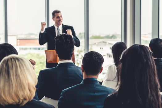 Group of business people meeting in a seminar conference . Audience listening to instructor in employee education training session . Office worker community summit forum with expert speaker .