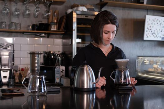 charming brunette woman barista making filter coffee in coffee shop. brewing coffee in cafe.