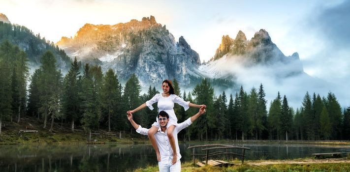 Happy couple of man carrying woman on neck and shoulders on vacation.