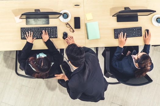 Business people wearing headset from top view in office working with computer to support remote customer or colleague. Call center, telemarketing agent service on telephone or video conference call.