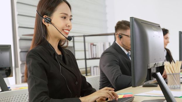 Business people wearing headset working in office to support remote customer or colleague. Call center, telemarketing, customer support agent provide service on telephone video conference call.