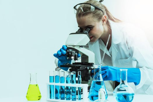 Young woman scientist working in chemical laboratory and examining biochemistry lab sample. Science technology medicine research and development study concept.