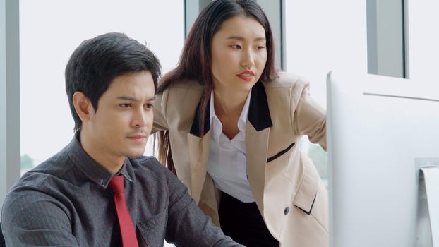 Two business people talk project strategy at office meeting room. Businessman discuss project planning with colleague at modern workplace while having conversation and advice on financial data report.