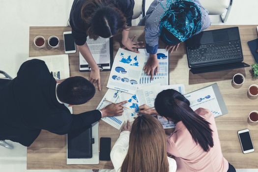 Top view of businessman executive in group meeting with other businessmen and businesswomen in modern office with laptop computer, coffee and document on table. People corporate business team concept.