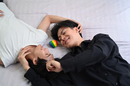 Homosexual couple lying down on bed, spending time together at home. LGBT, pride, relationships and equality concept.