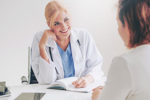 Woman doctor is talking and examining female patient in hospital office. Healthcare and medical service.