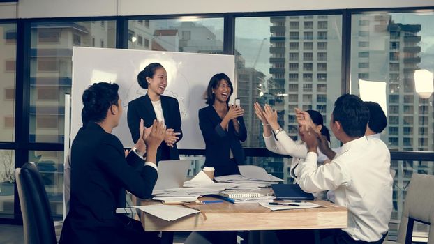 Successful Asian businessman and businesswoman celebrate project success while attending a group meeting. Victory and winner concept.