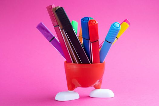 Red stand with white legs and colored markers isolated on a pink background
