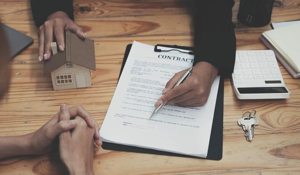 Real estate agent talked about the terms of the home purchase agreement and asked the customer to sign the documents to make the contract legally, Home sales and home insurance concept..