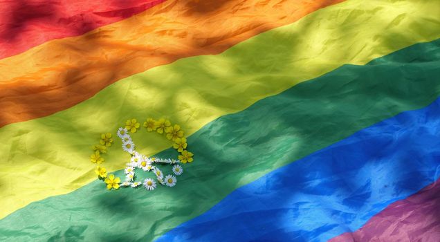 Symbol of peace with flowers on rainbow LGBT flag background in pride month of dignity and diversity. Close up, copy space, paste text, sunny summer day.